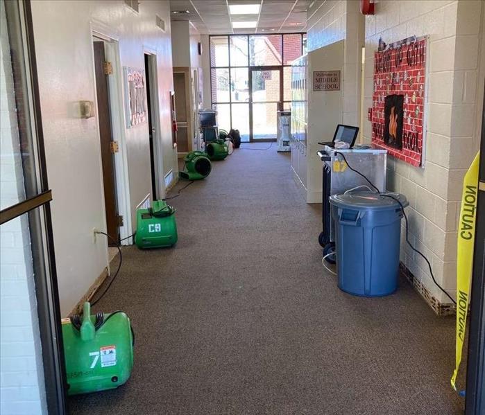 Dehumidier and air movers set up in a middle school hallway