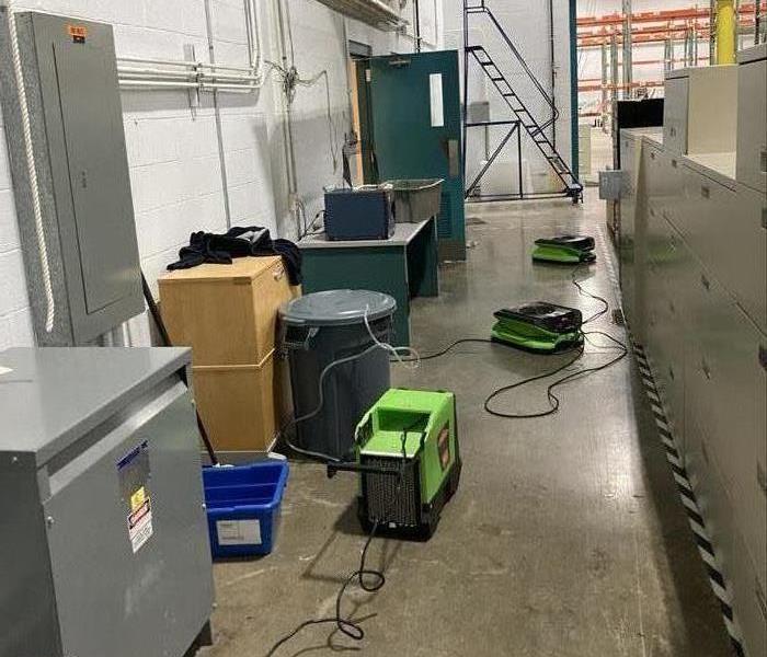  A dehumidifier and two air movers in an aisle with a dry floor in a warehouse