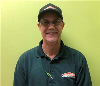 Male employee in a green shirt with a black hat on