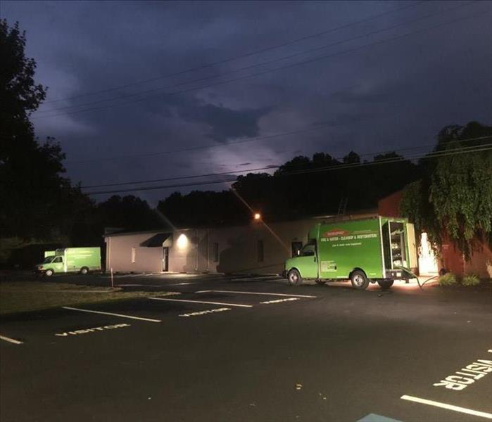 2 Green SERVPRO trucks outside of a commercial building