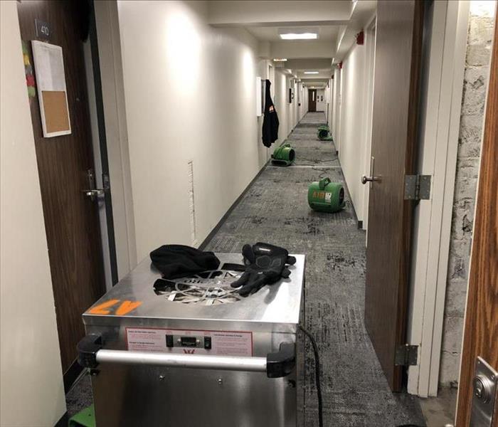 A dehumidifier and three air movers in a long hallway