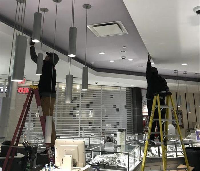 2 men on ladders cleaning in a jewelry store