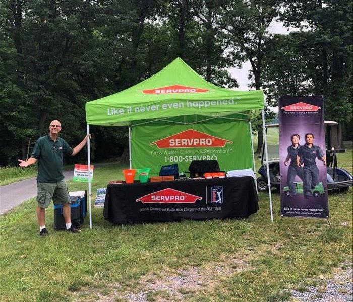 Man standing beside a green SERVPRO pop-up vendor tent