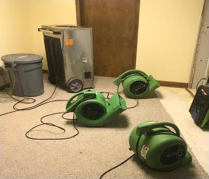 Dehumidifiers and air movers drying a basement
