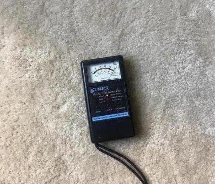 Moisture meter reading red on a carpet